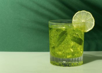 نوشیدنی سبز با نعنا و تزیین لیمو که بک گراند سبز داره.